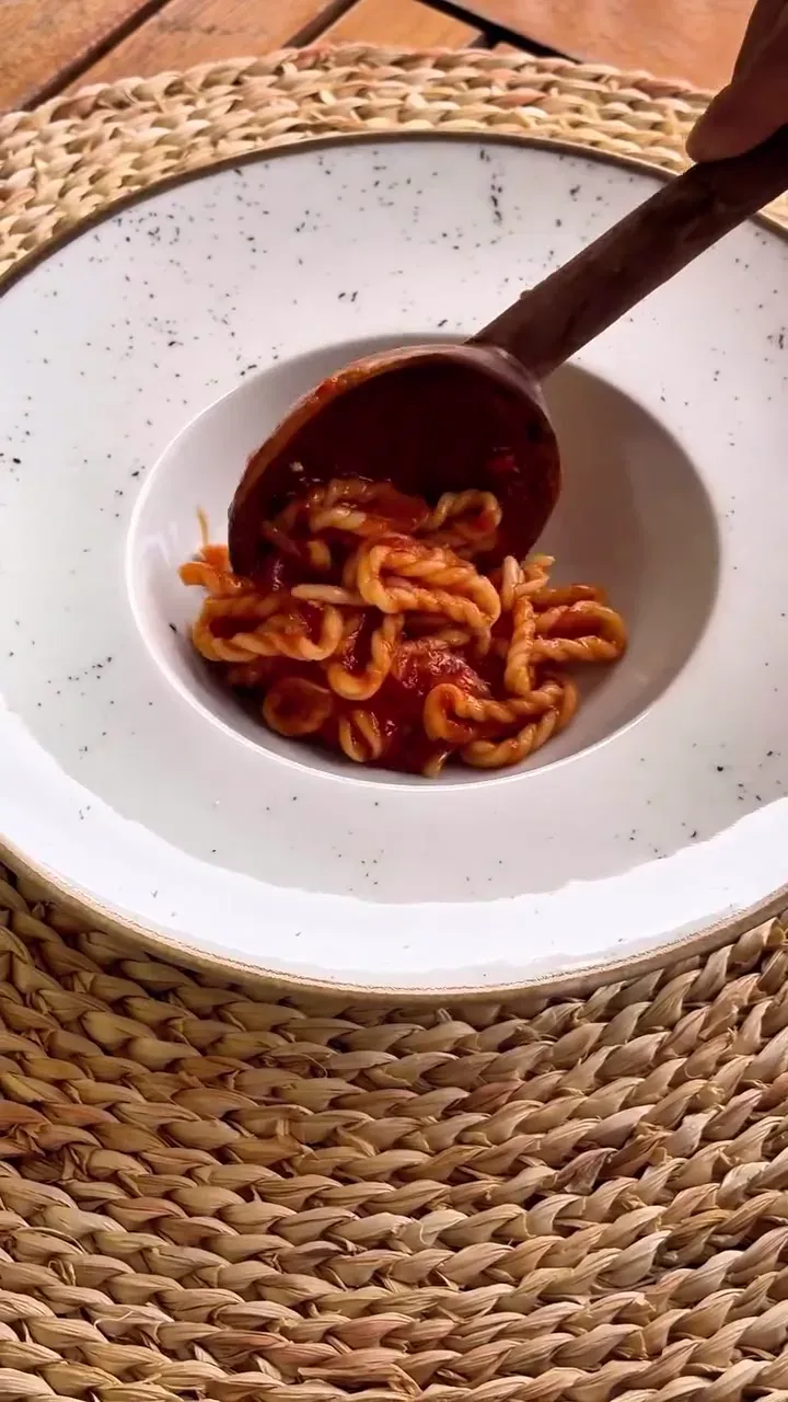 Un piatto di lorighittas al sugo, con un mestolo di legno